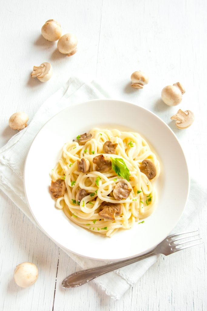 creamy mushroom pasta recipe on a table with a fork and uncooked mushrooms