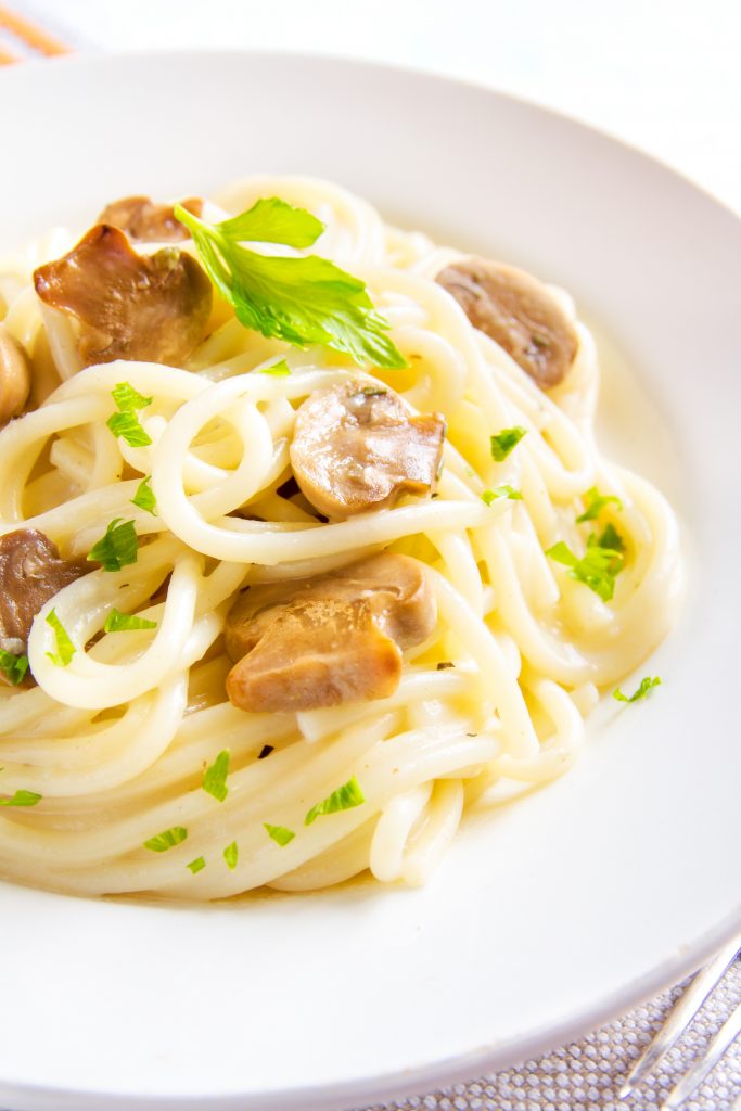 close up on a creamy mushroom pasta recipe with green garnish