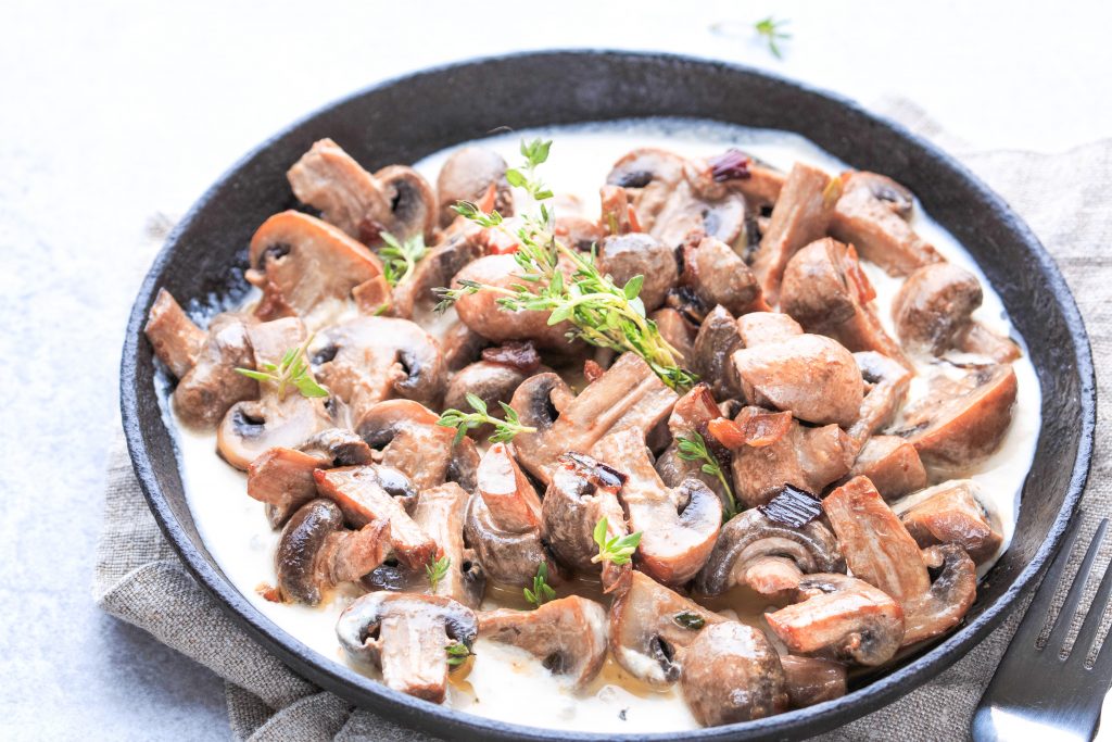 mushrooms cooking in a pan with garnish