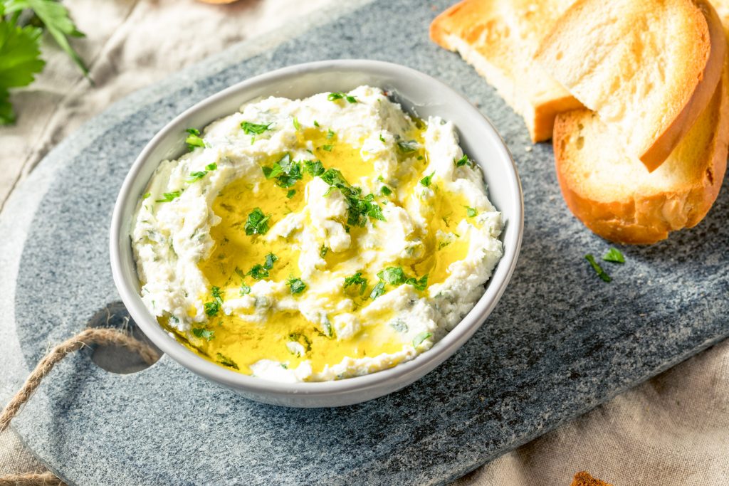 goat cheese dip with olive oil and bread on a serving tray