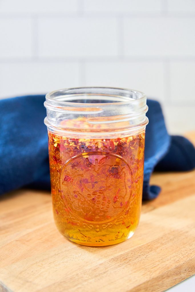 hot honey in a glass jar on a cutting board