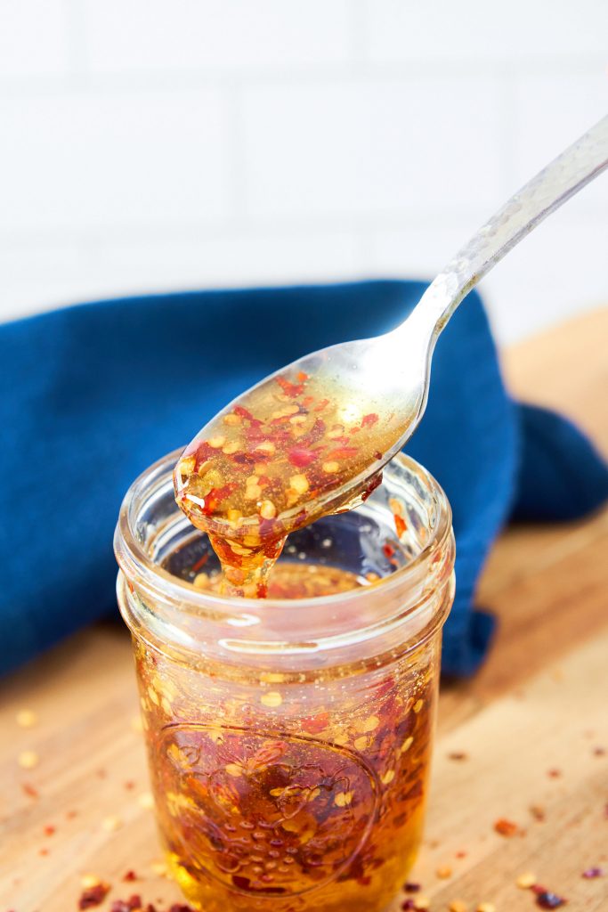 close up on a spoon scooping out a hot honey recipe from a jar