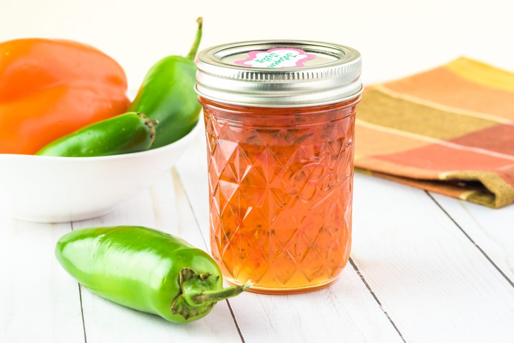 peppers with various colors behind jalapeno jelly in a jar