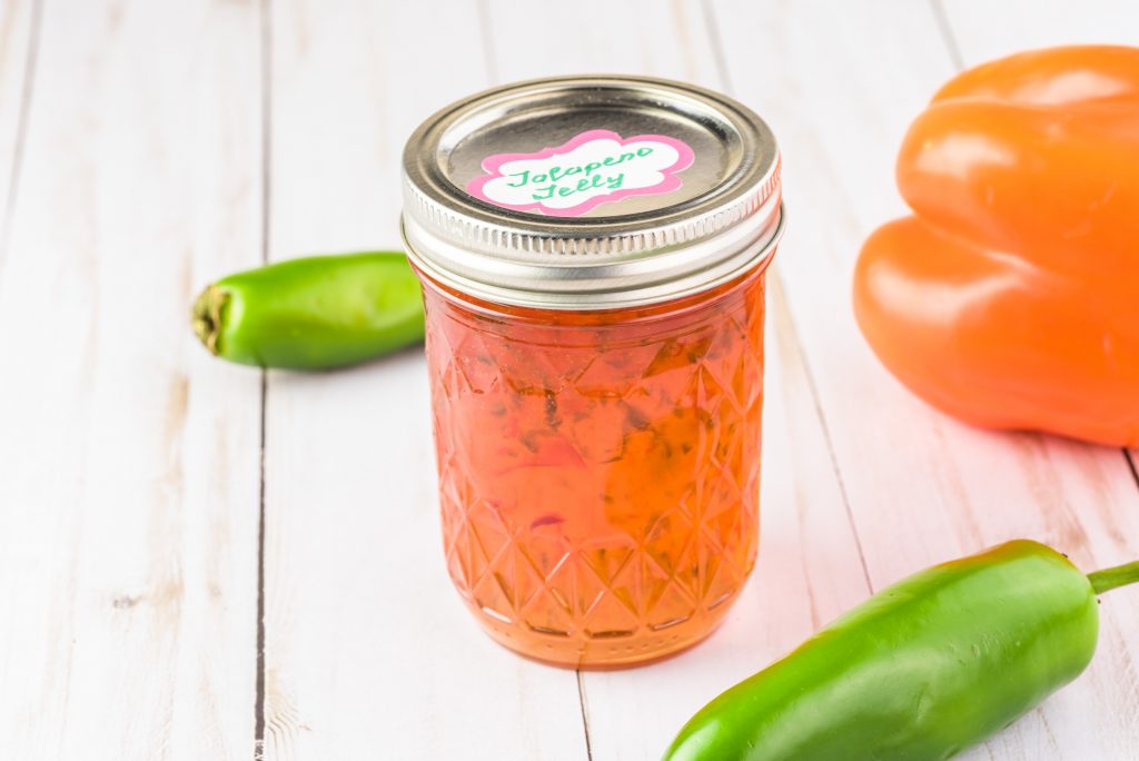 multiple peppers of different colors surrounding jalapeno jelly in a jar