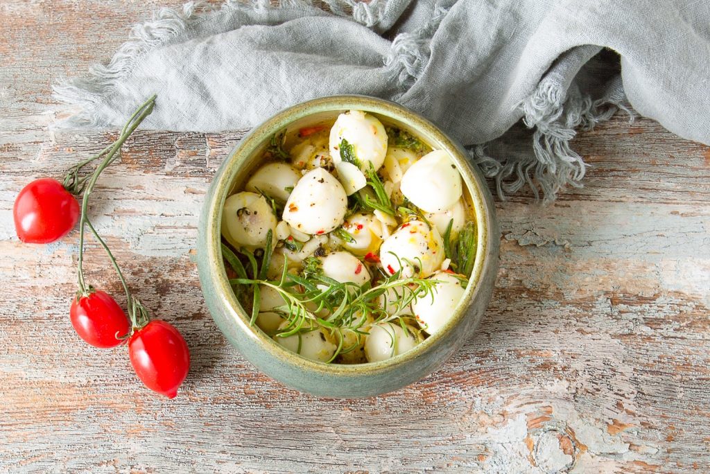 mini marinated mozzarella balls in a bowl with tomatoes