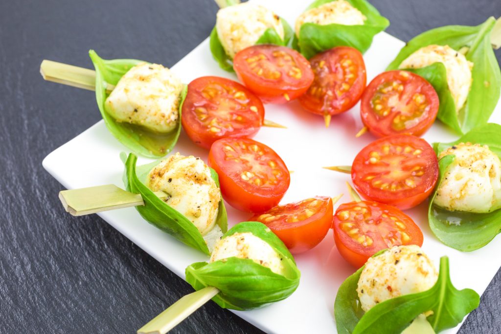 serving marinated mozzarella balls on a plate with basil leaves