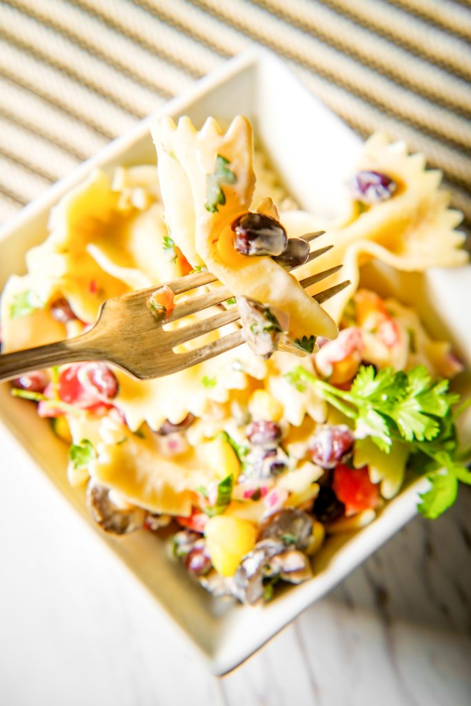 fork and piece of pasta in corn pasta salad with black beans and veggies