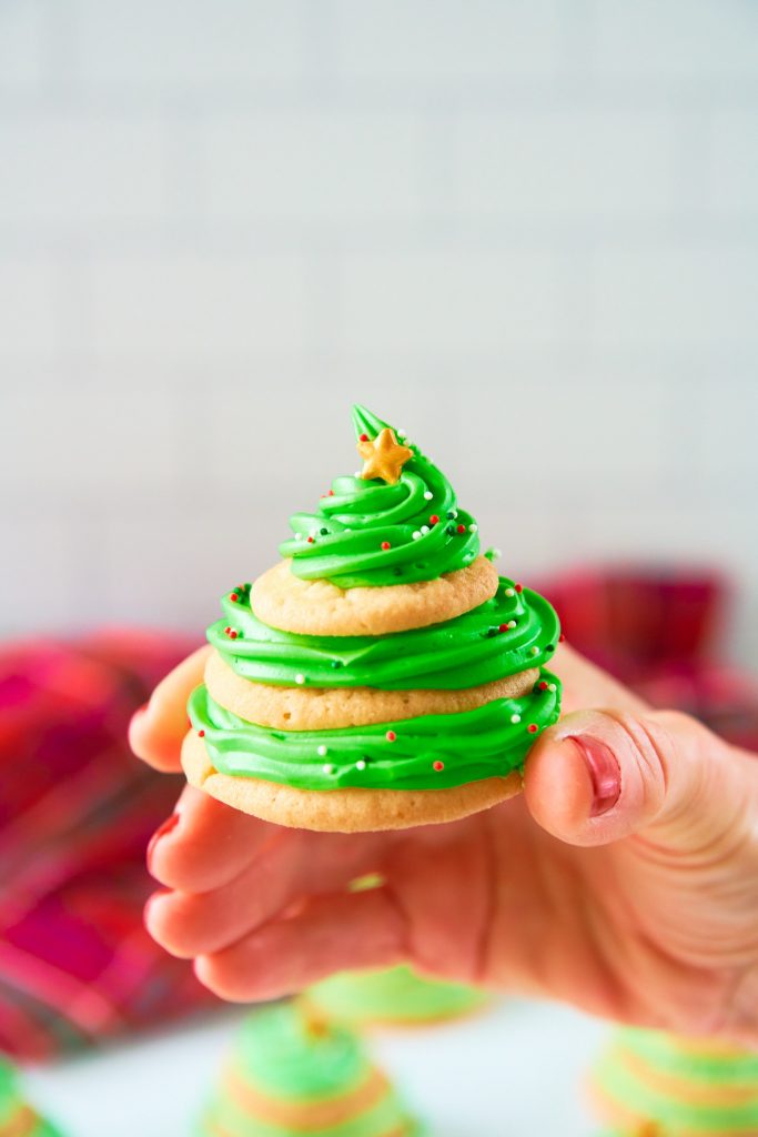 hand holding Christmas tree shaped stacked sugar cookie with icing