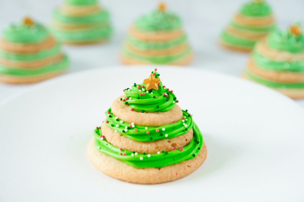 stacked sugar cookie Christmas tree on a plate with other cookies in the back