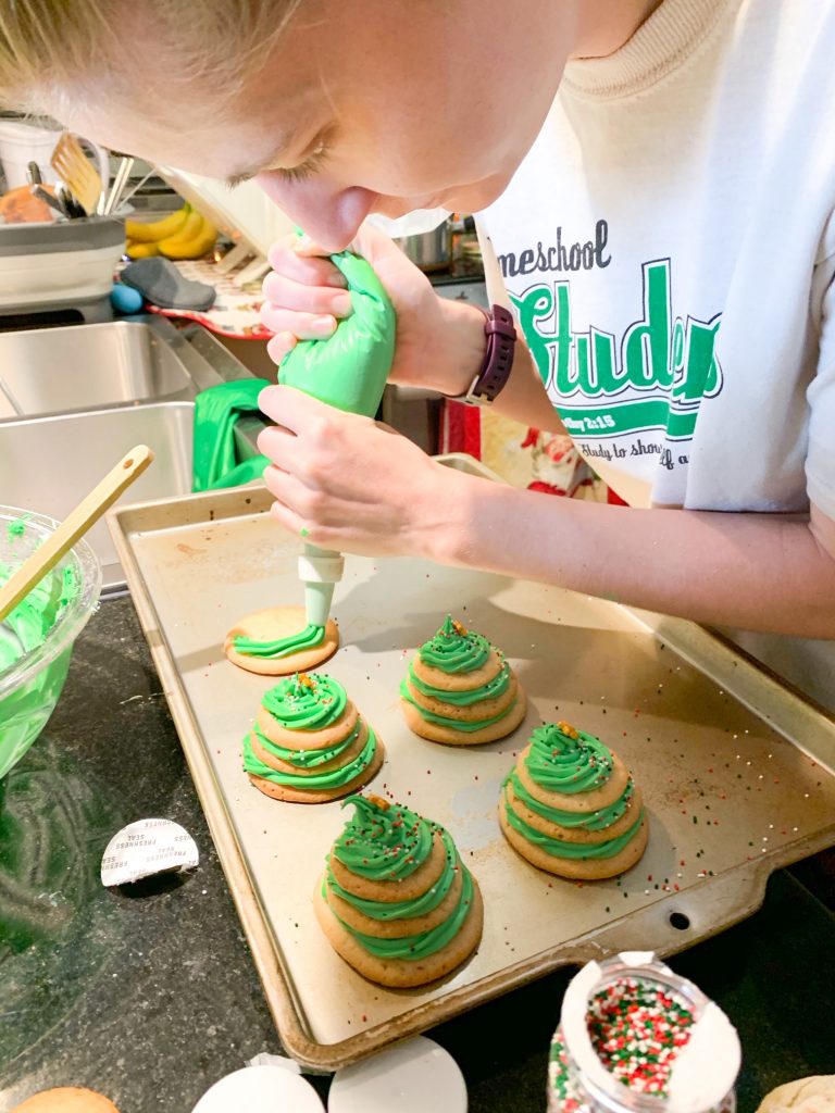 Victoria Yore piping icing onto stacked sugar cookie Christmas trees
