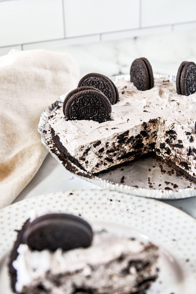 slice of vegan Oreo cheesecake in the foreground with cake in the background