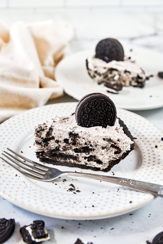 fork lying on a plate with vegan Oreo cheesecake in the background