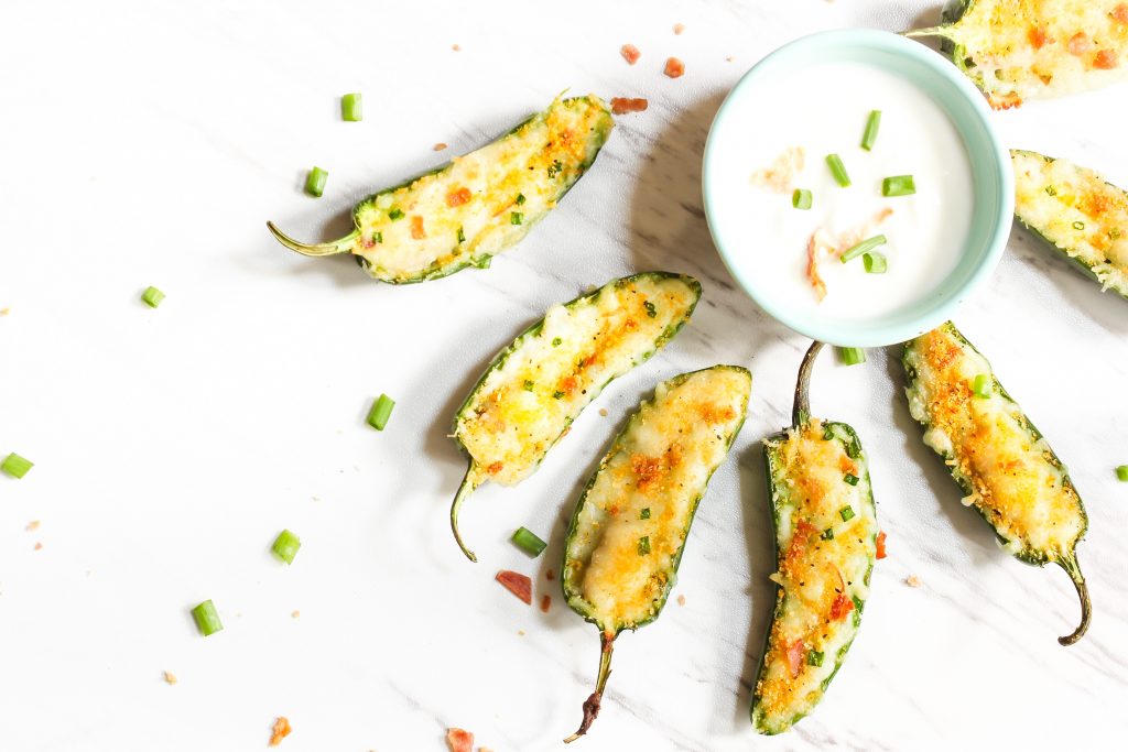 vegan jalapeno poppers surrounding a bowl of sour cream