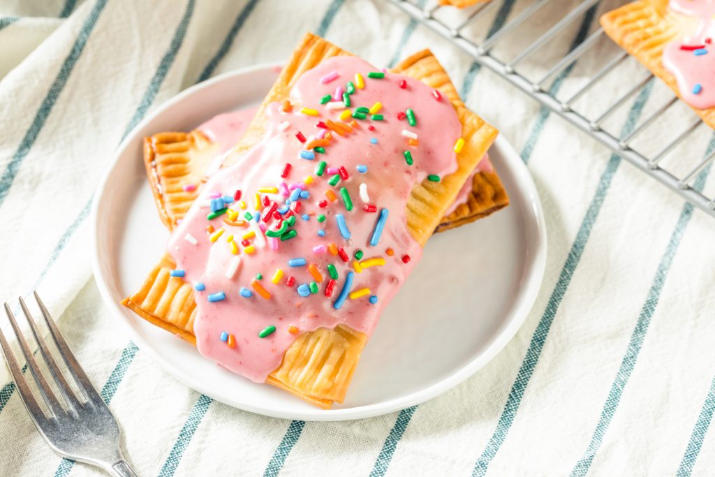 two vegan pop tarts stacked on a white plate with strawberry glaze