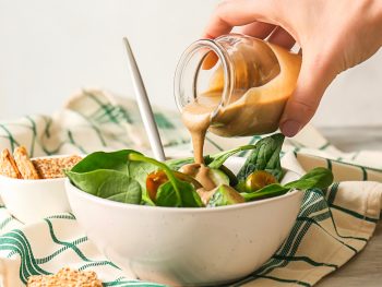 maple tahini dressing being poured over salad