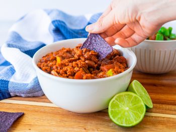 tortilla chip being dunked into vegan chili