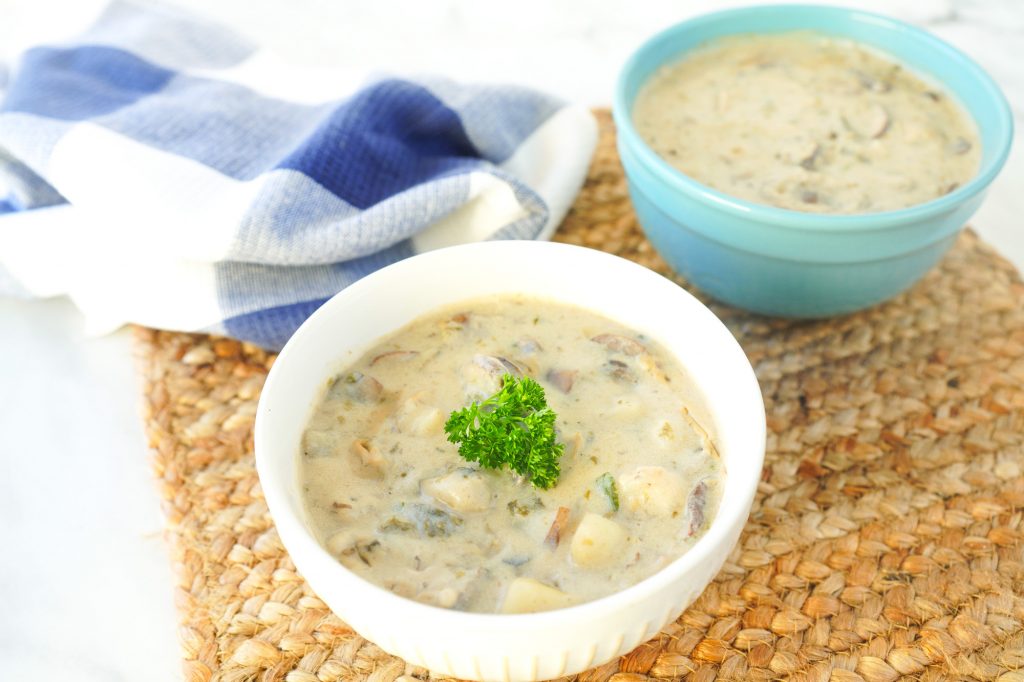 Dos tazones de sopa de almejas vegana sobre un mantel individual