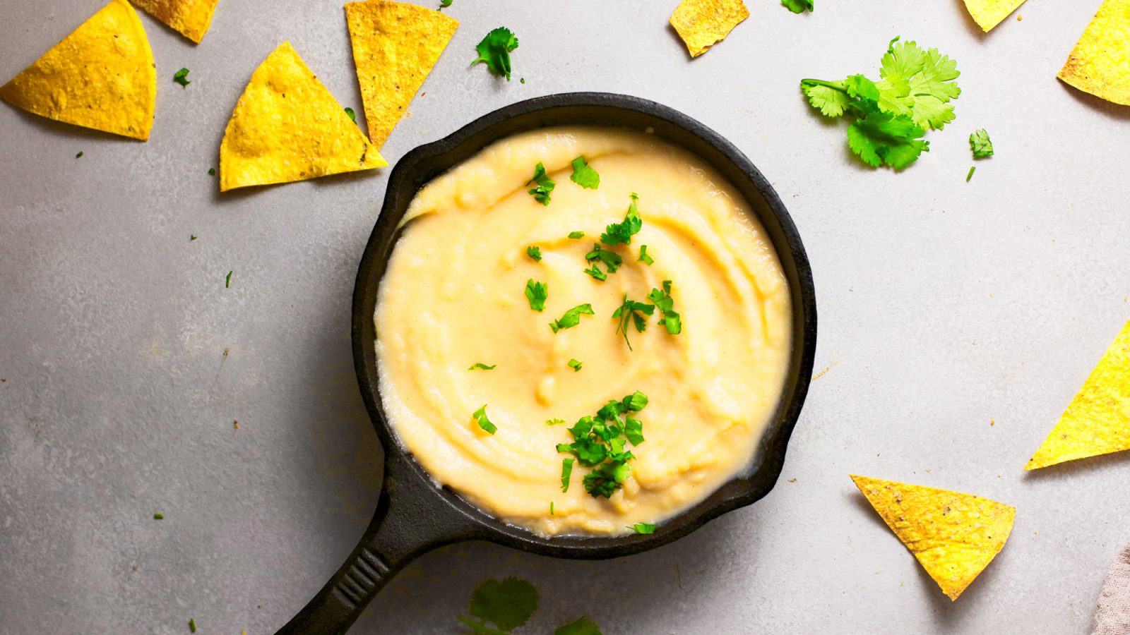 vegan queso in cast iron skillet with chips