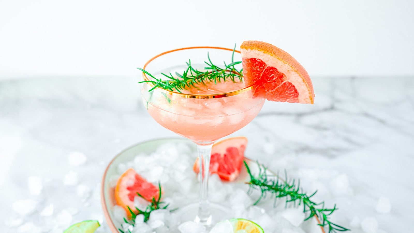 pink grapefruit cocktail with rosemary and crushed ice on tray