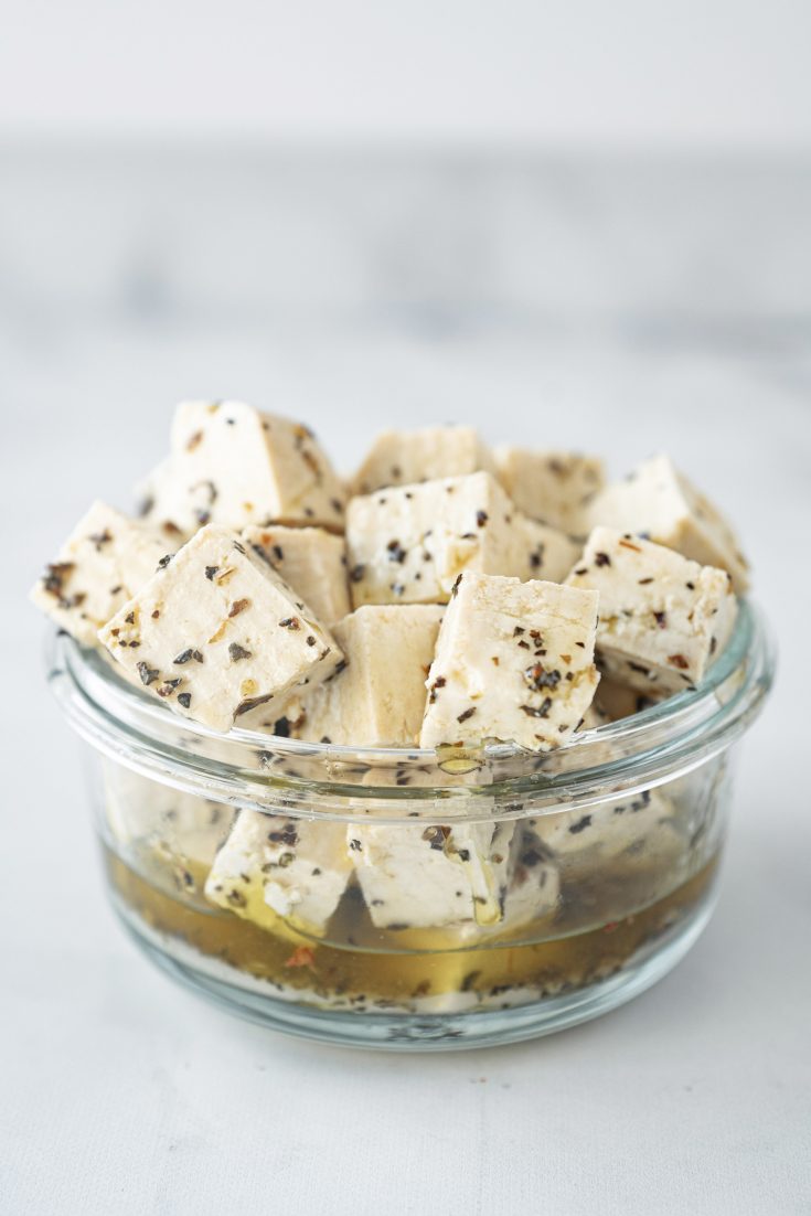 vegan feta cheese in glass jar with spices