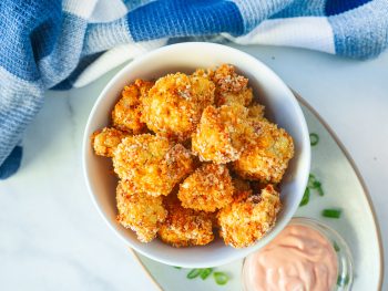 vegan crispy baked cauliflower in a bowl with dipping sauce