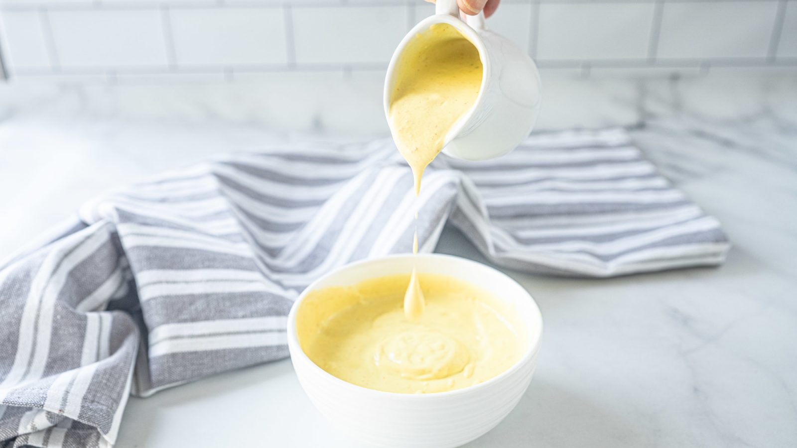 vegan hollandaise sauce being poured into a bowl