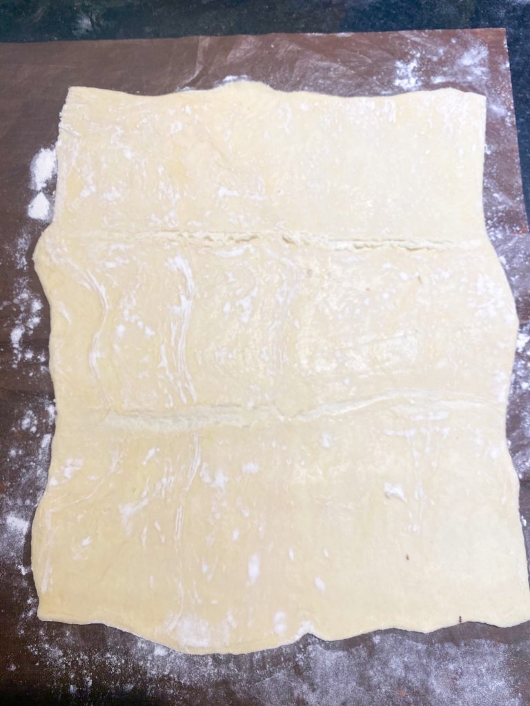 Puff pastry dough laid out on a surface with flour.