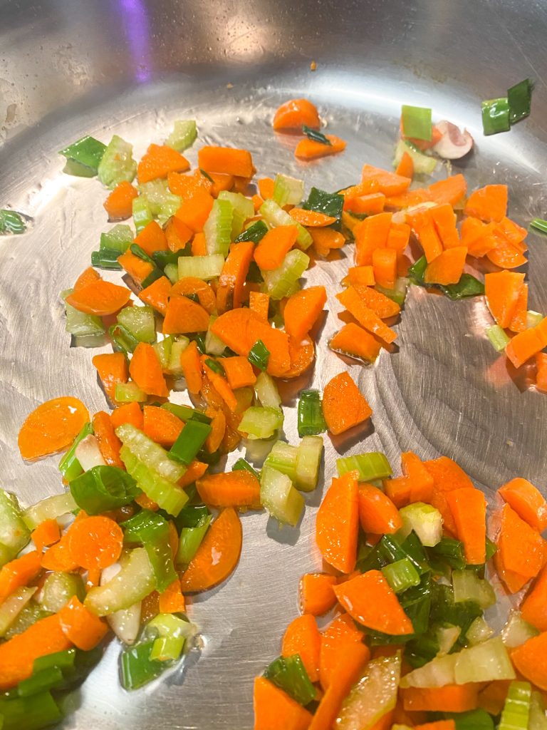chopped carrots and green onions sauteing in a pan.