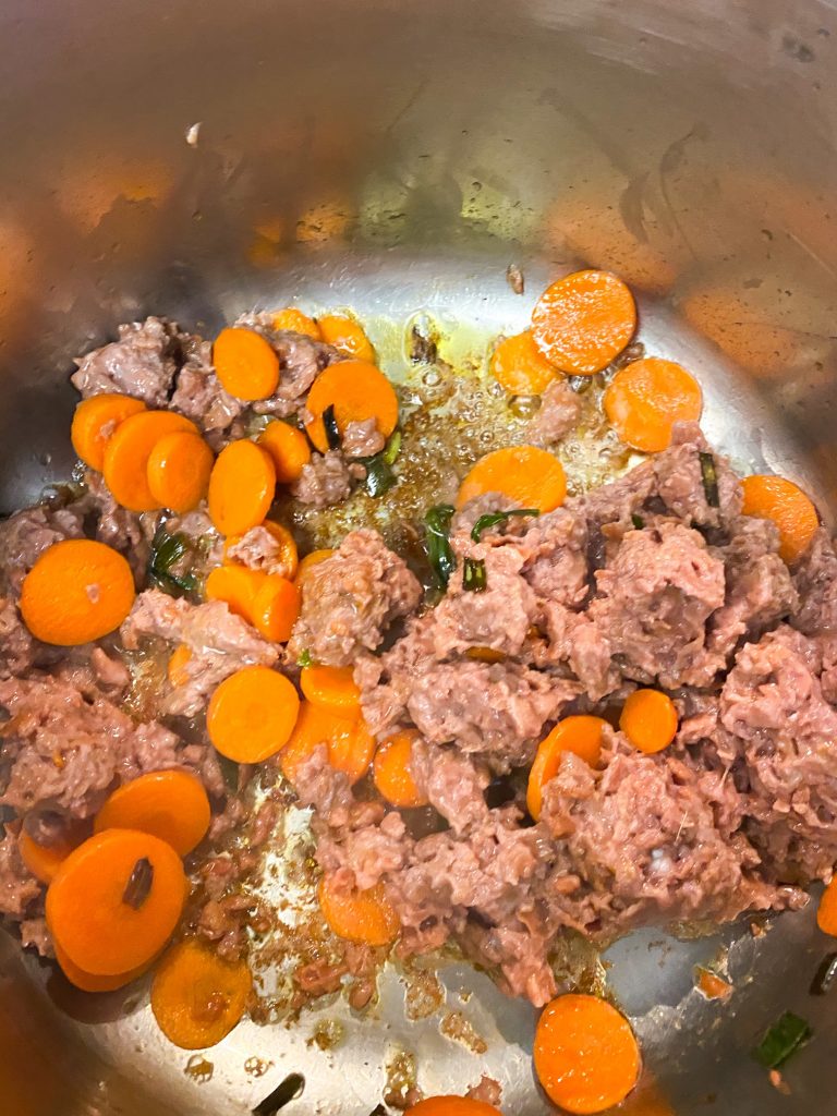 Vegan beef and chopped carrots cooking in a pot.