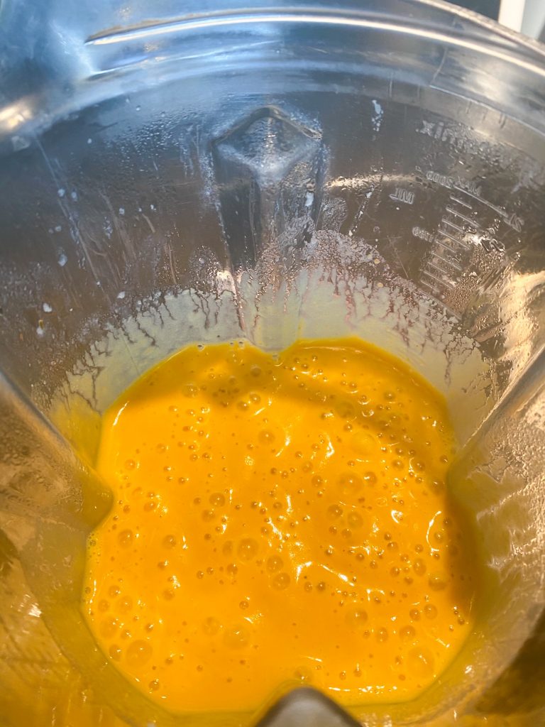 Orange, blended carrot soup in a blender.