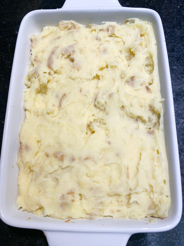 Unbaked casserole dish of vegan shepherd's pie with mashed potatoes.