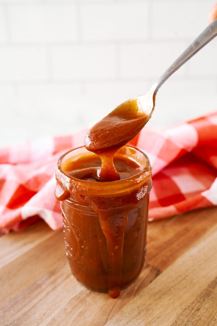 vegan bbq sauce in a storage jar with a spoon scooping it out