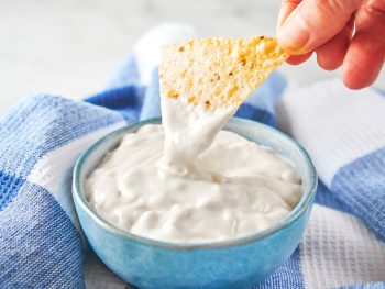 chip scooping out vegan sour cream from a bowl