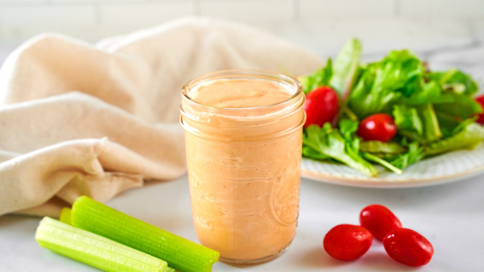 vegan thousand island dressing in jar with salad in the background