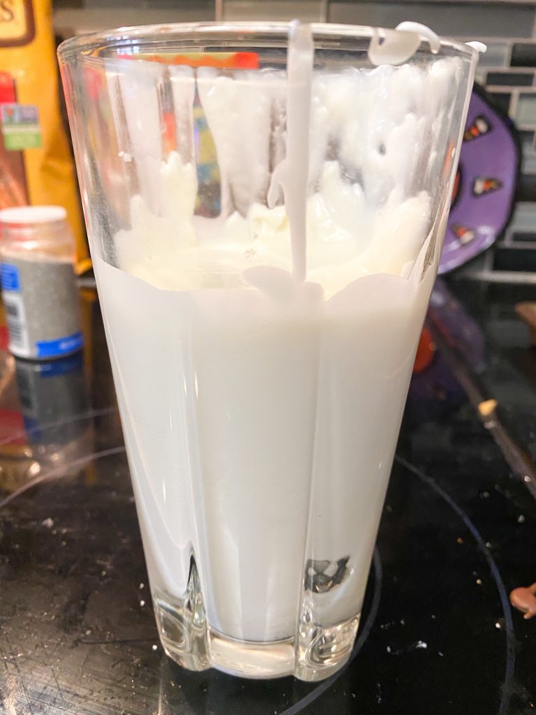 Melted white chocolate for dipping pretzels in a glass cup