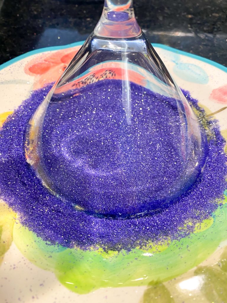 Rim of cocktail glass dipped in sparkling, bright purple sanding sugar.
