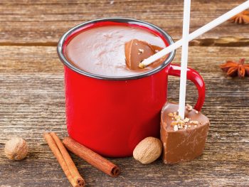 hot chocolate sticks that are vegan being dipped into a red mug