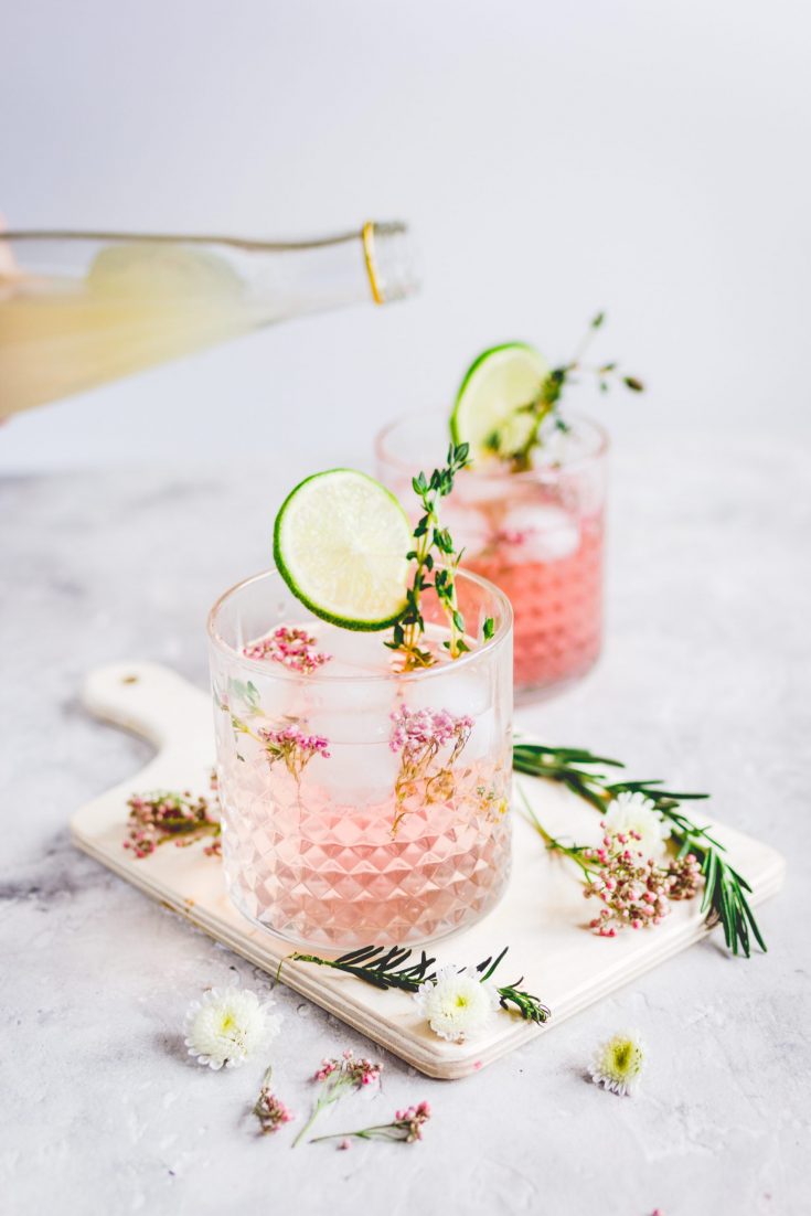 pink vodka lemonade being poured into a glass with garnish