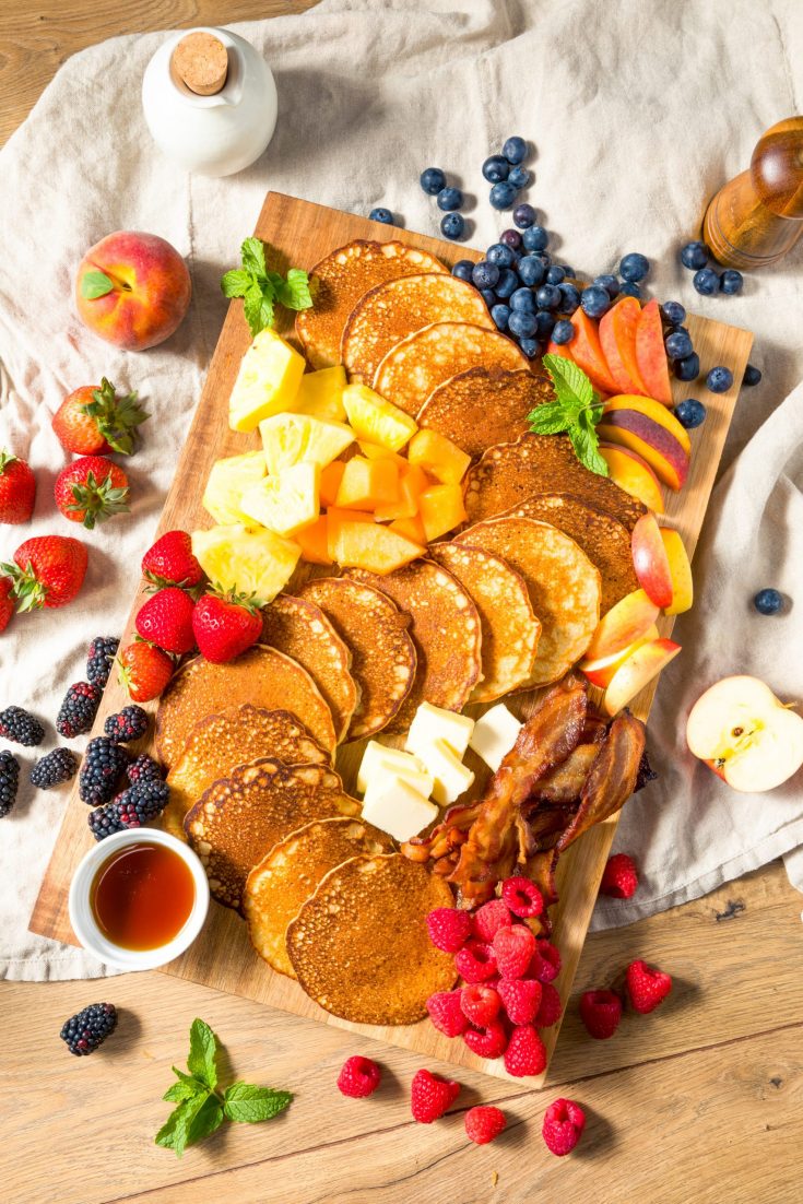 breakfast charcuterie board with pancakes, fruit, vegan bacon and more