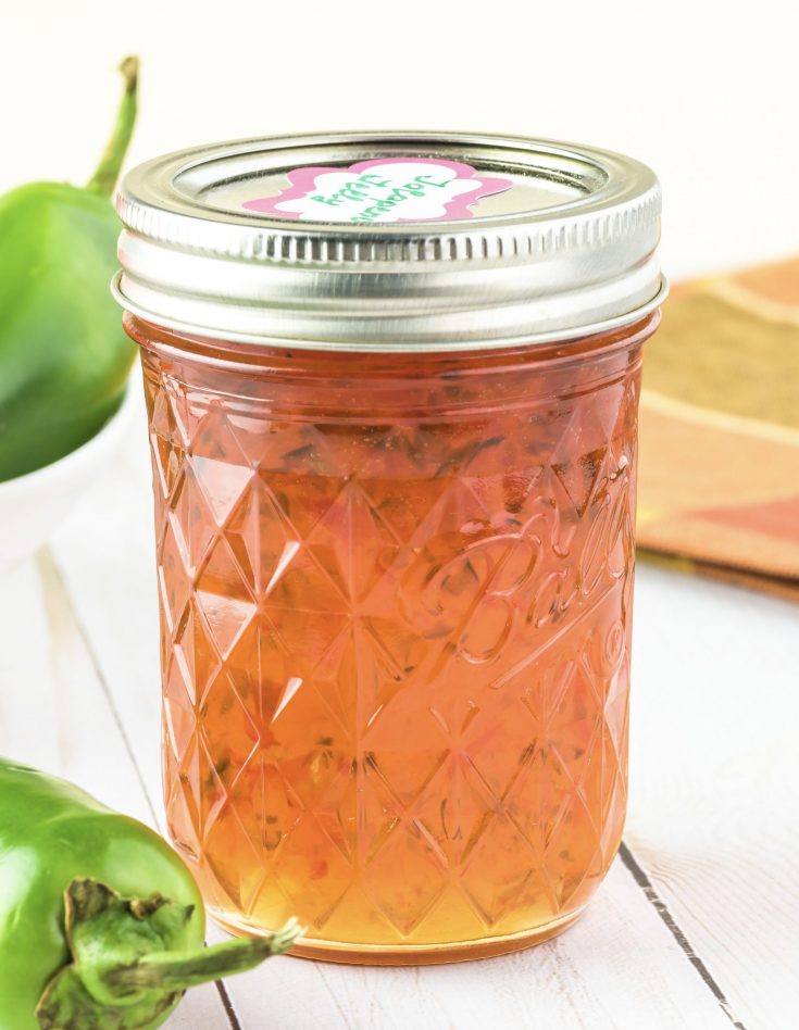 close up of jalapeno jelly in a jar with peppers around it