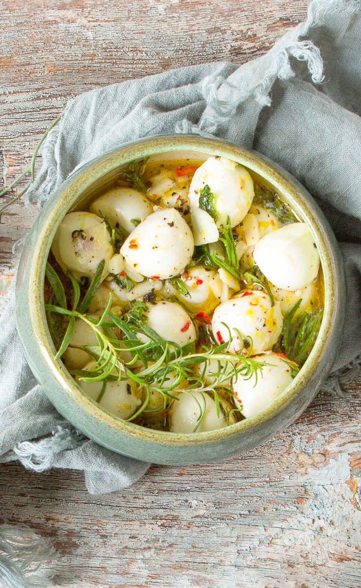 marinated mozzarella balls in a bowl with fresh rosemary