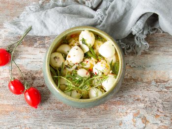 marinated mozzarella balls in a bowl with fresh veggies