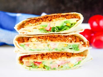vegan crunchwrap supreme taco bell copycat on a white counter with tomatoes in the background