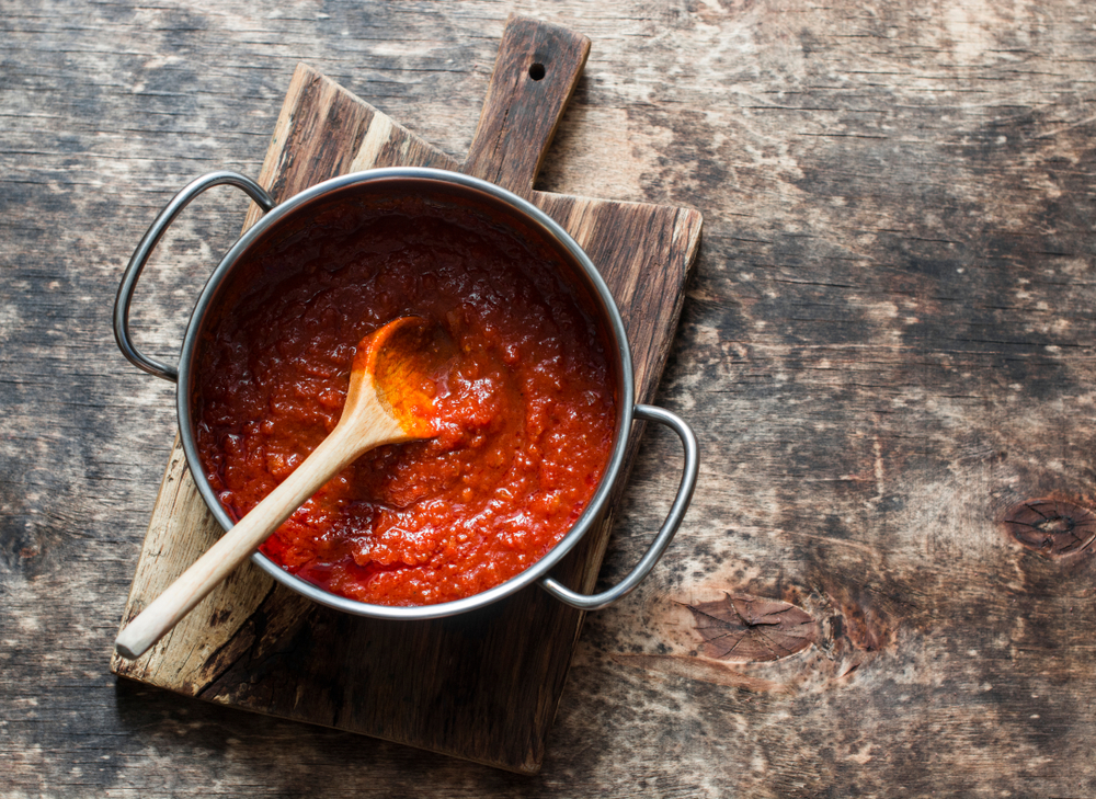 vegan tomato pasta sauce in a bowl with a brown spoon resting on the side 