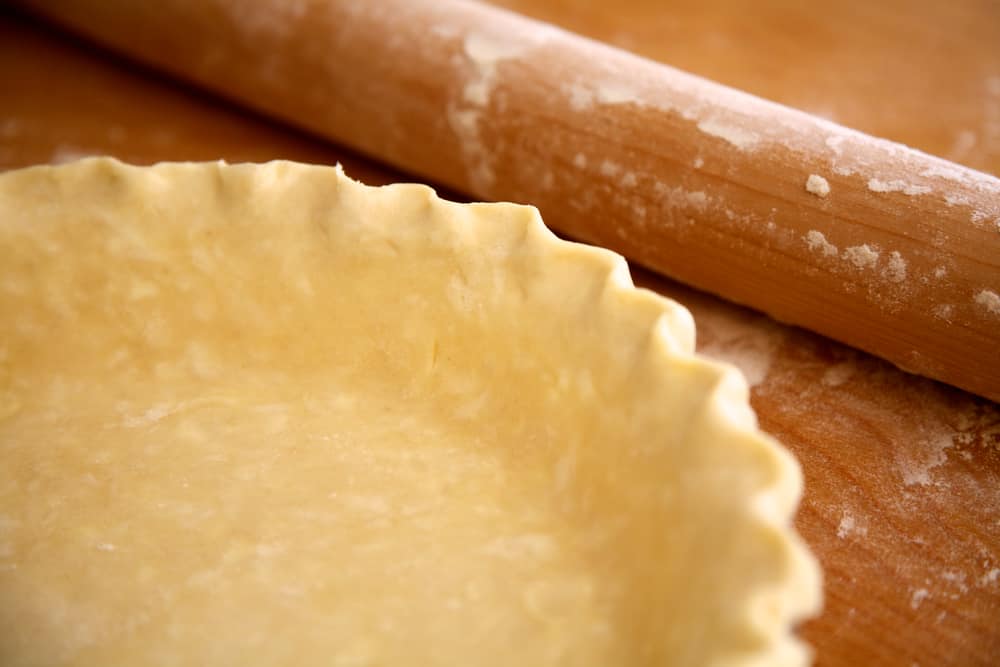 Close up of pie crust next to a rolling pin.