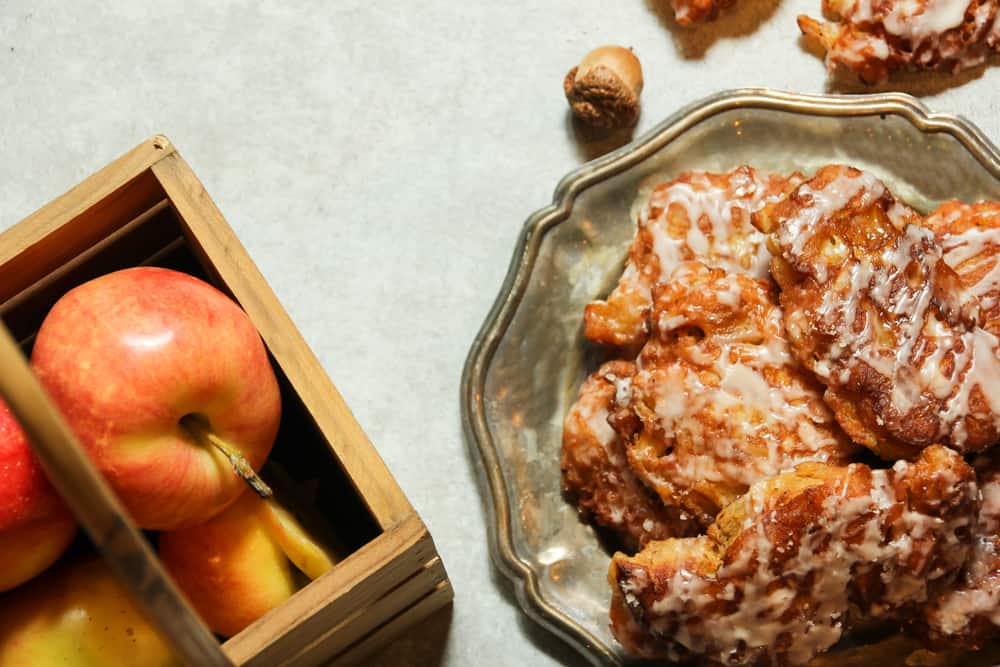 Looking down at a plate of apple fritters next to a crate of red apples.