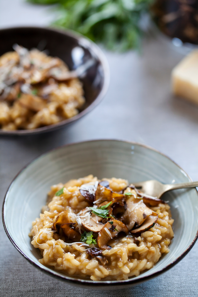 Two bowls of vegan risotto topped with mushrooms.