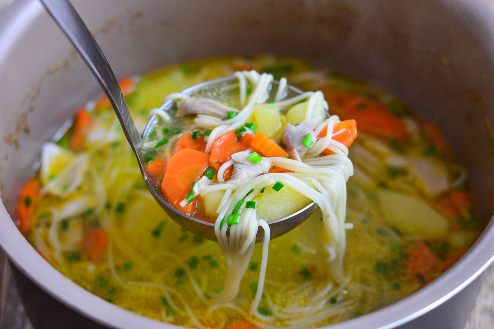 Vegan chicken noodle soup ladled out of the pan