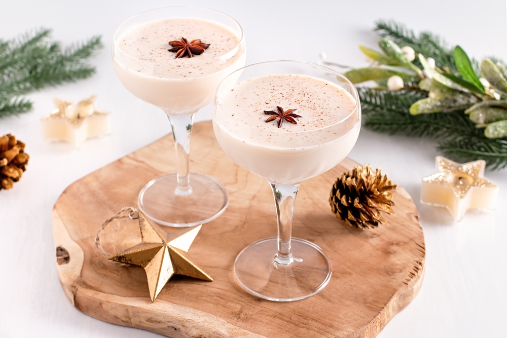 Eggnog on wooden tray, Christmas cocktail in coupe glass, top view.