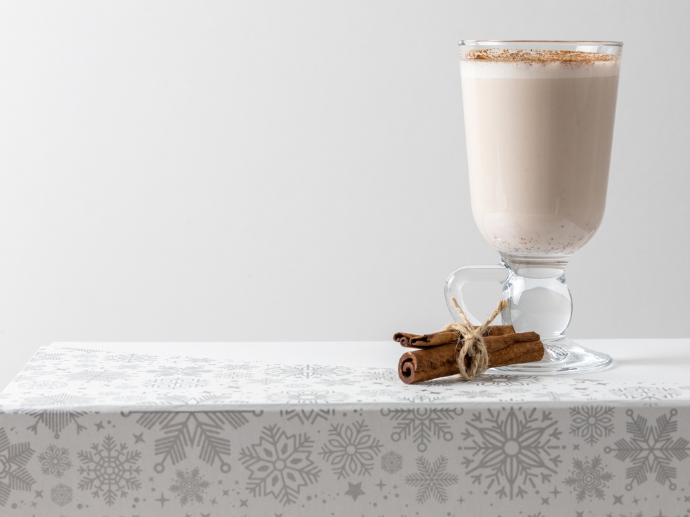 Vegan Christmas cocktail Eggnog and cinnamon sticks on a white background. Healthy holiday drink, dairy-free cocktail.
